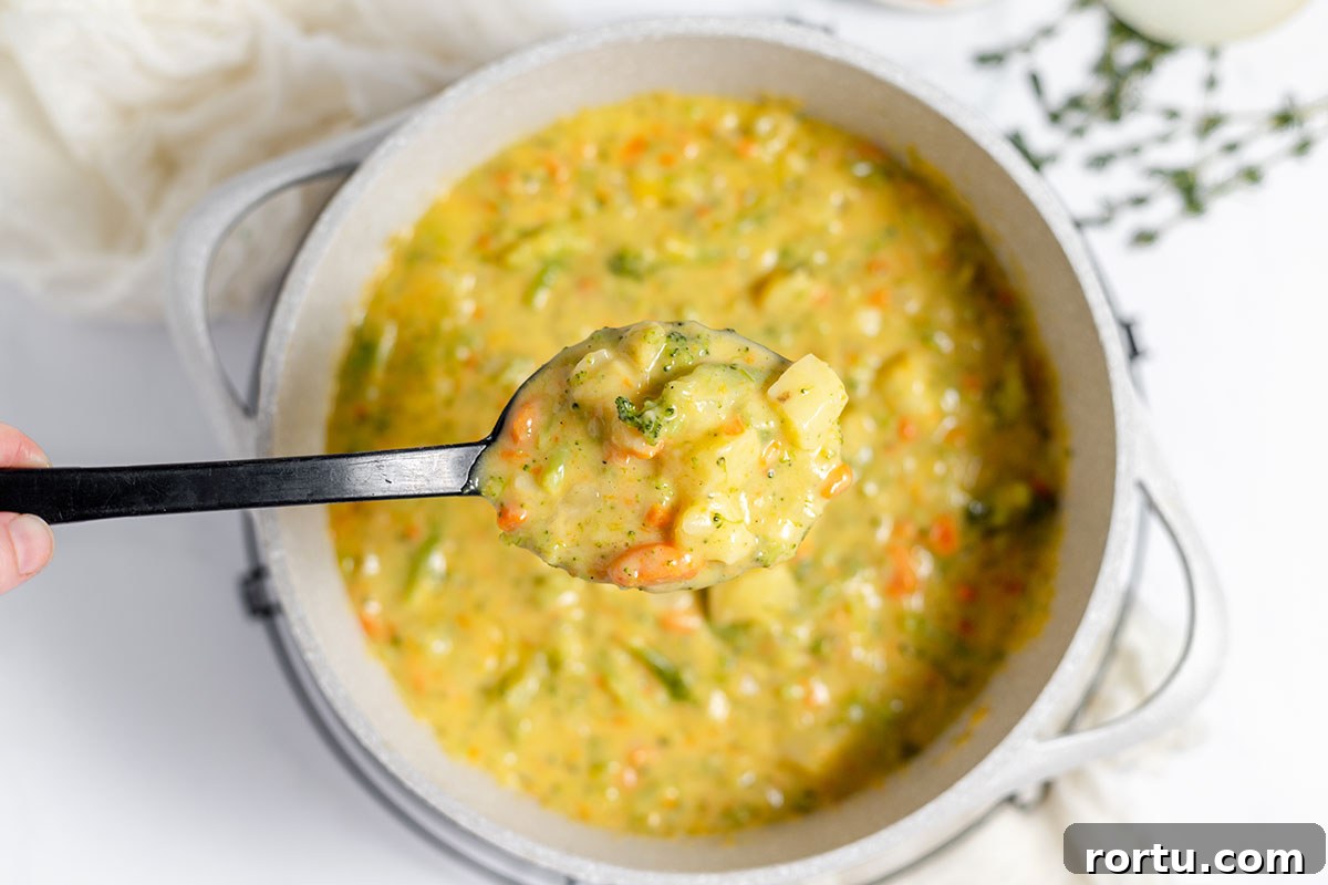 Creamy Broccoli, Potato & Cheddar Soup Recipe 10 A large spoonful of Broccoli Potato Cheese Soup held over the stock pot.