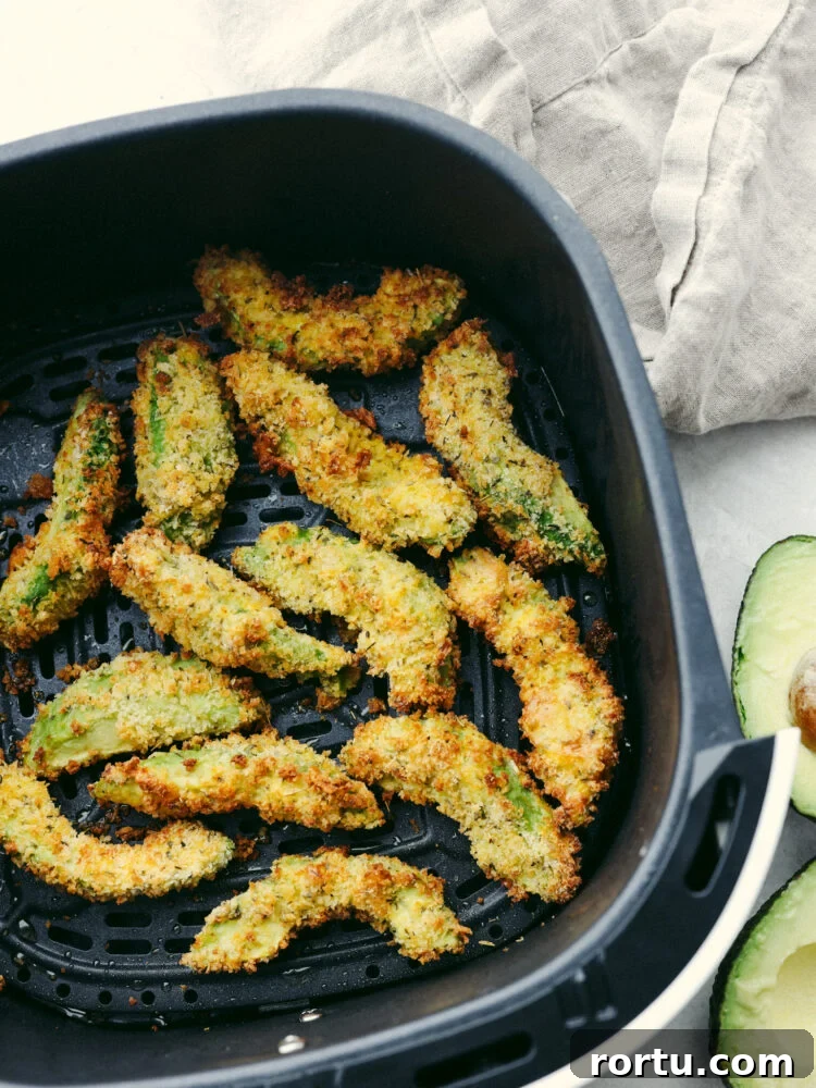 Avocado fries in the basket of an air fryer.