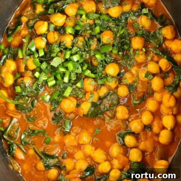 Chickpeas and spinach in a tomato, creamy sauce in the slow cooker for a vegetarian Chana Saag recipe.