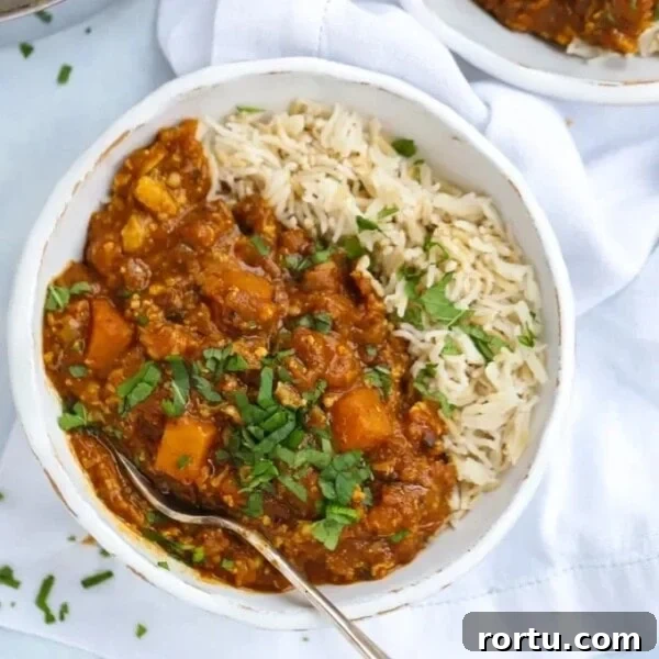 A bowl with butternut squash curry with rice and a fork ready to eat.