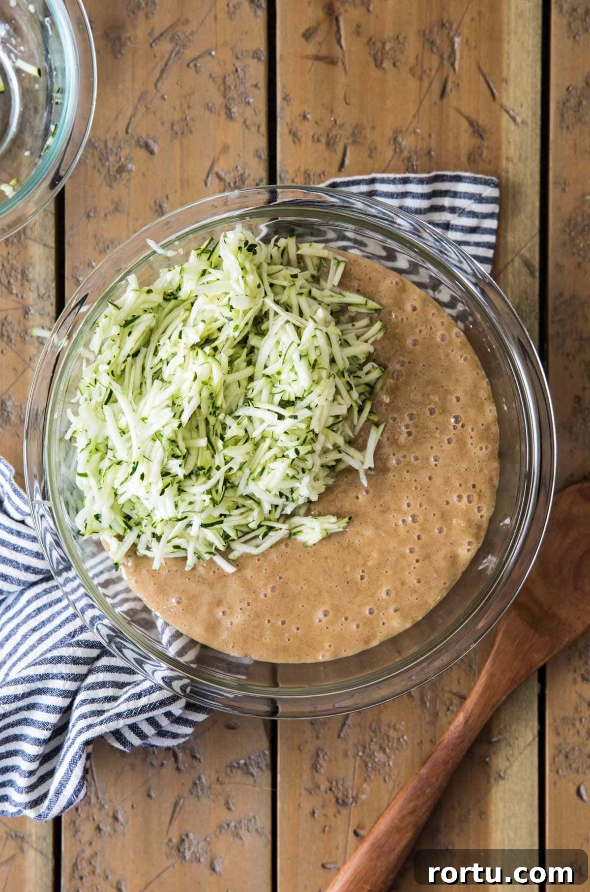 batter with shredded zucchini in glass bowl
