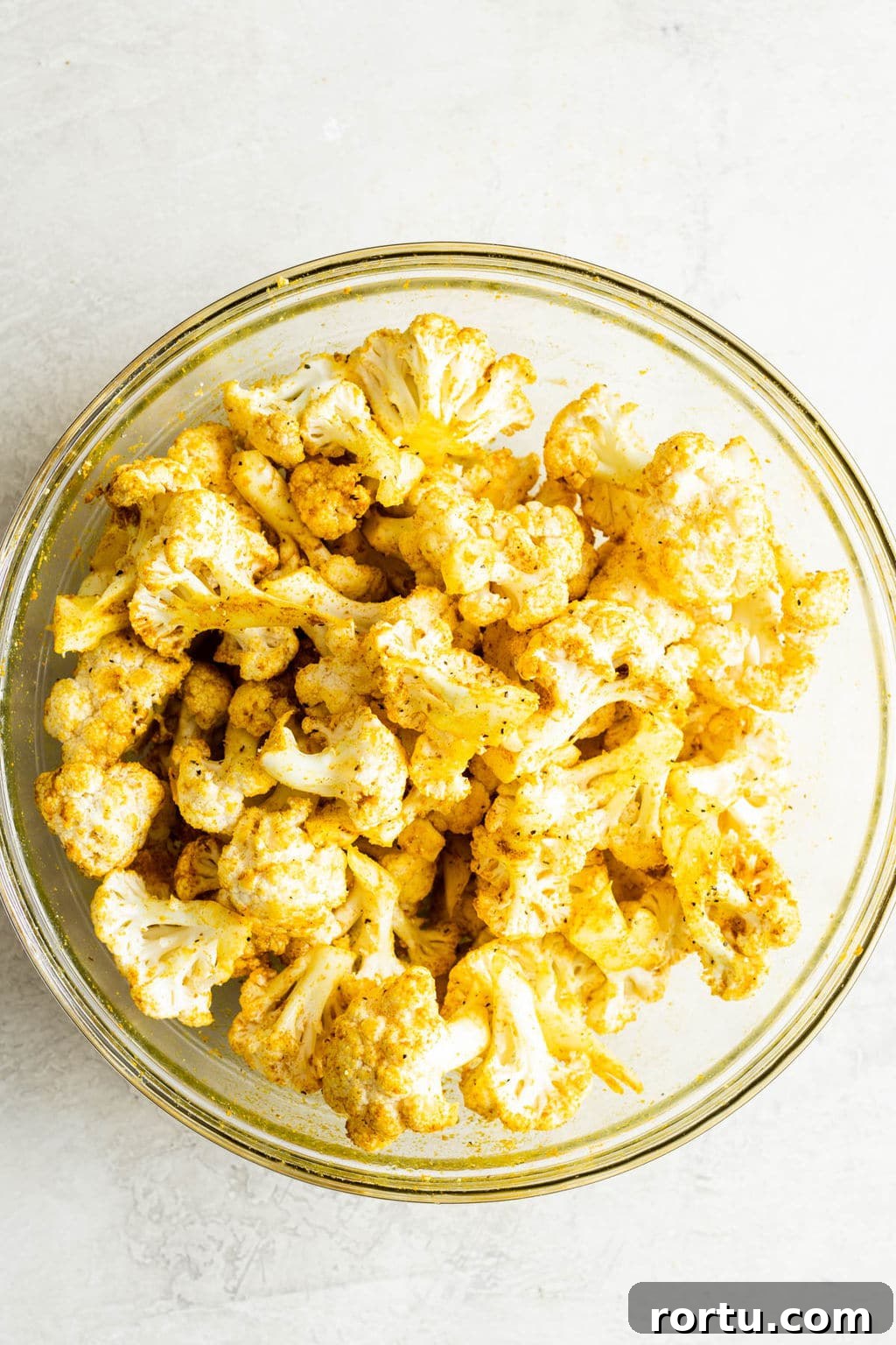 Crispy Roasted Cauliflower with Curried Spice Rub 4 a glass bowl filled with yellow curry-seasoned cauliflower florets.