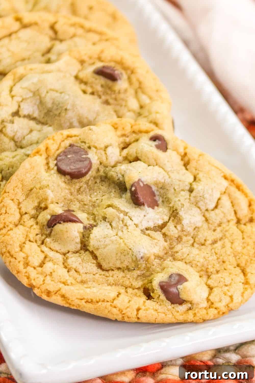 Chocolate Chip Cookies Without Butter — Made with Oil 4 close-up view of a chocolate chip cookie without butter, served on a white rectangular plate.
