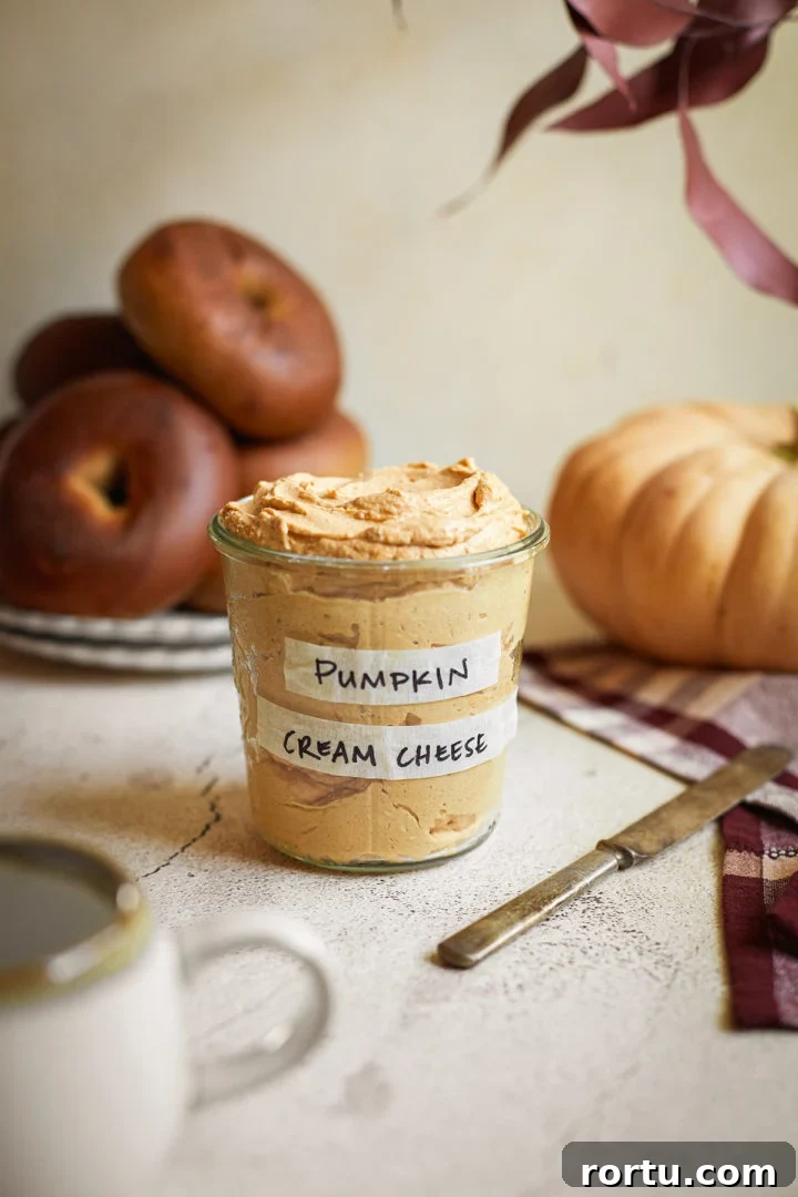 jar of pumpkin spice cream cheese next to a plate of bagels