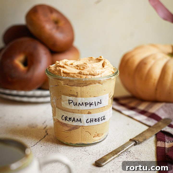 a jar of pumpkin cream cheese spread next to a plate of bagels
