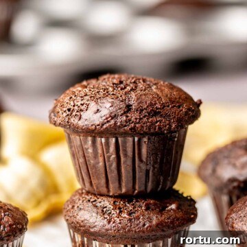 Two chocolate banana muffins stacked on top of each other.