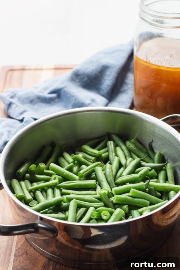 Cut green beans in a pot with ham stock in a jar. 