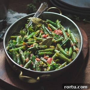 Mexican green beans with tomatoes, oregano and bay leaf in a copper gratin pan with brass handles.