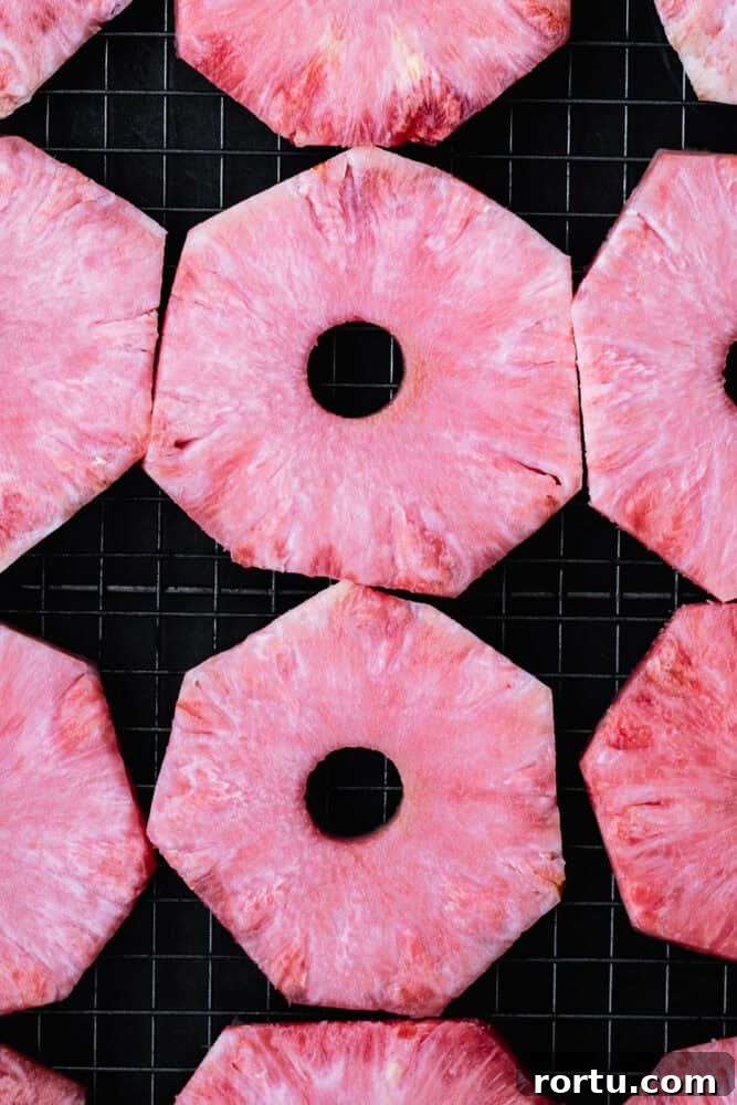sliced pink pineapple rings on black background