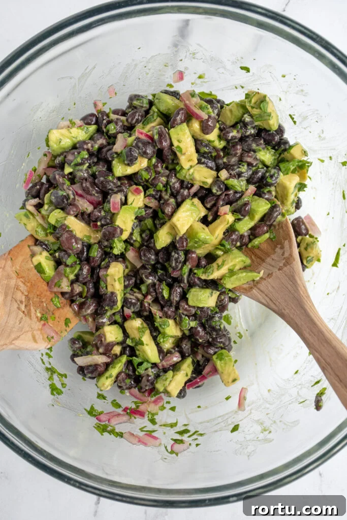 Mixing the black bean avocado salsa together in a mixing bowl.