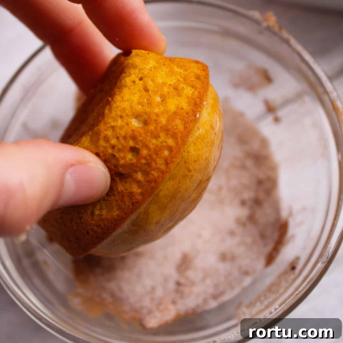 Dipping the butter dipped muffin into the cinnamon sugar coating.