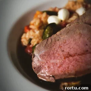 Tender Slow-Roasted Eye Round: Juicy, Melts in Your Mouth 15 Sliced eye round roast on a white platter over risotto