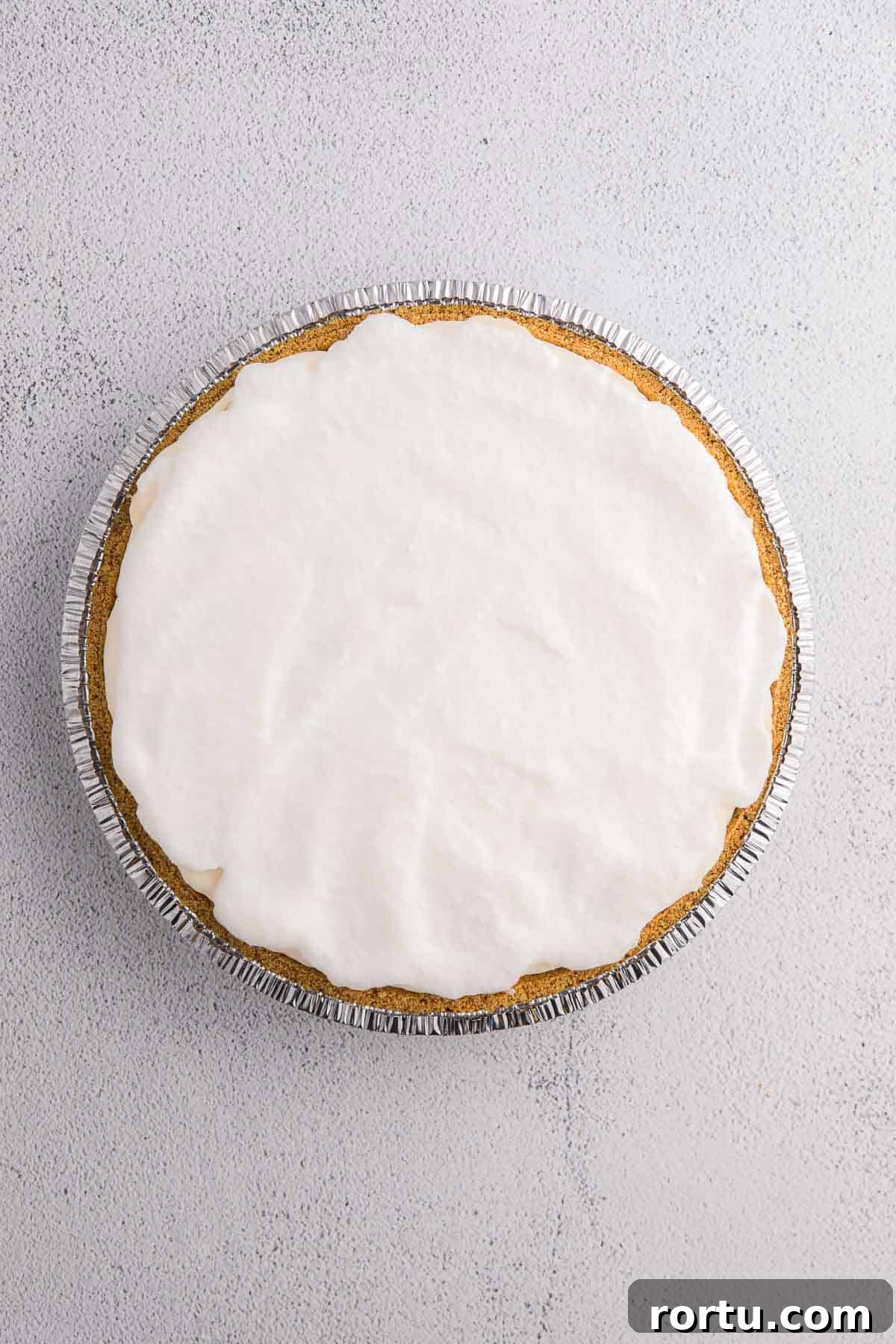 Layer of whipped topping spread over pie filling in a graham cracker crust.