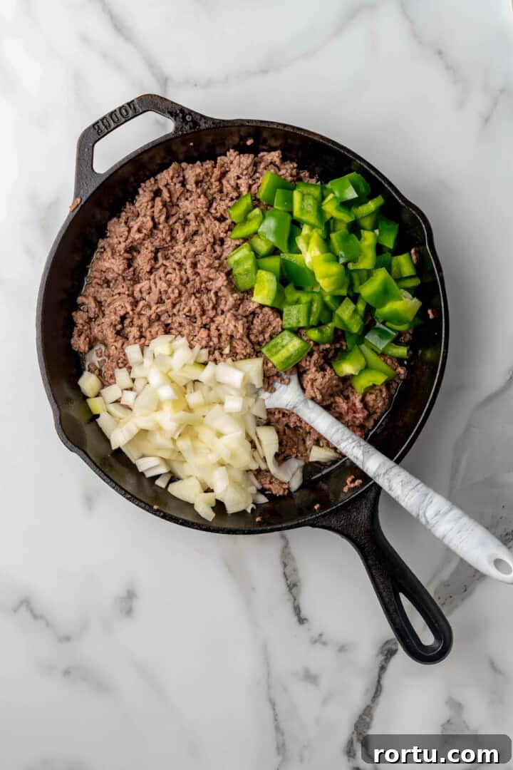 Philly Cheesesteak Sloppy Joes Recipe — Savory Sandwich Twist 4 cooking beef peppers and onions in skillet