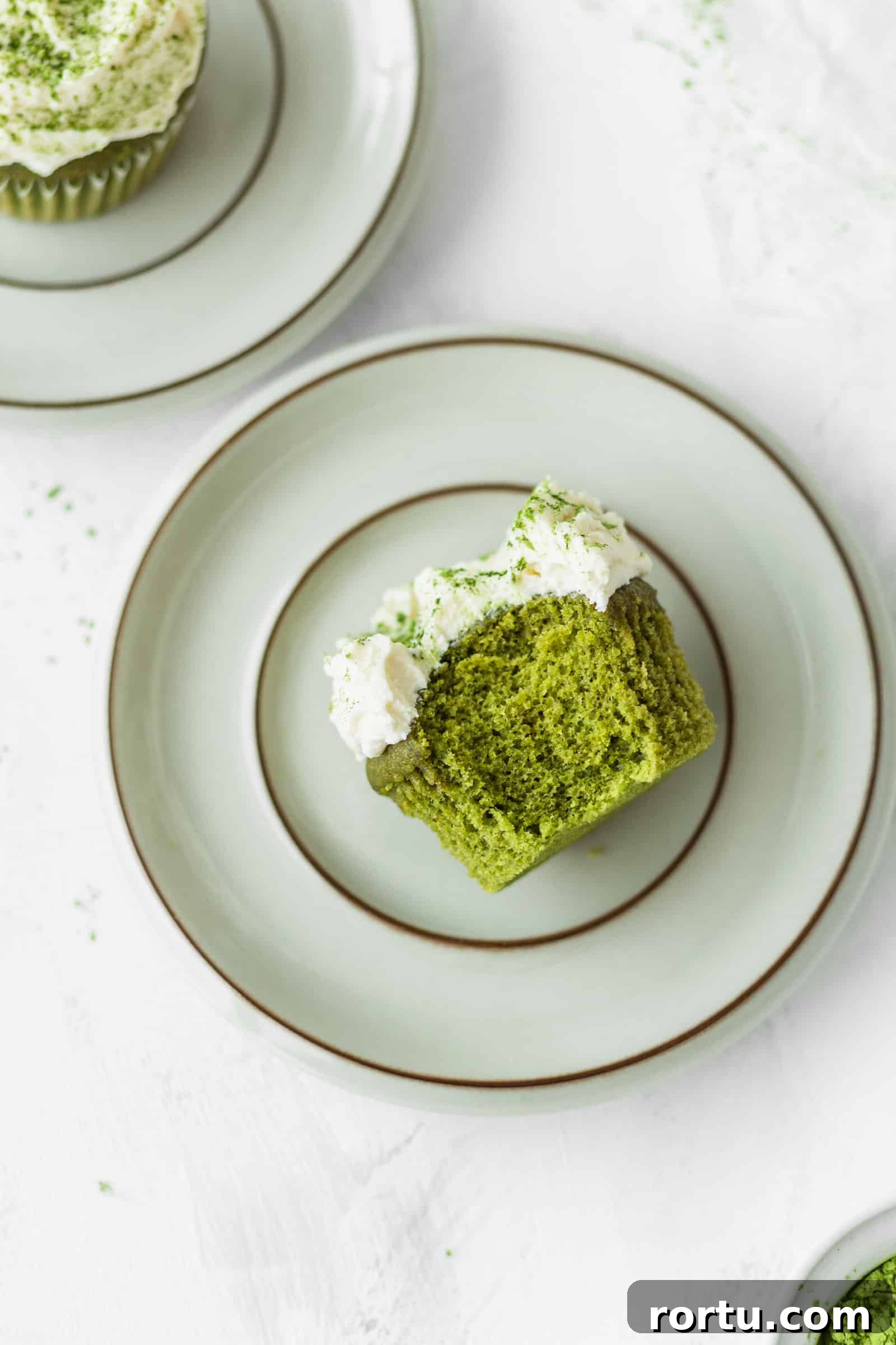 Fluffy Matcha Cupcakes: How to Make Moist Green Tea Cupcakes (Video) 12 Half-eaten fluffy matcha cupcake with white chocolate frosting on a plate