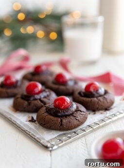 chocolate thumbprint cookies with chocolate ganache and maraschino cherries on wire cooling rack