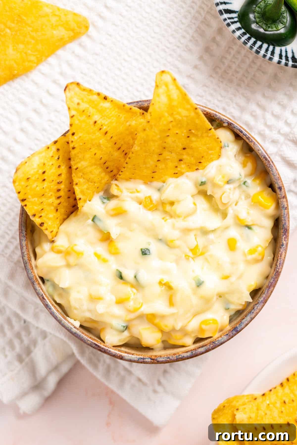 Spicy Jalapeño Corn Salad Bowl 2 An overhead image of jalapeno corn in a wooden bowl with tortilla chips on the side.