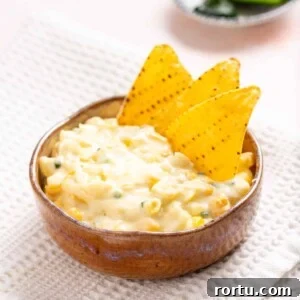 Spicy Jalapeño Corn Salad Bowl 14 An image of jalapeno corn in a wooden bowl with tortilla chips on the side.