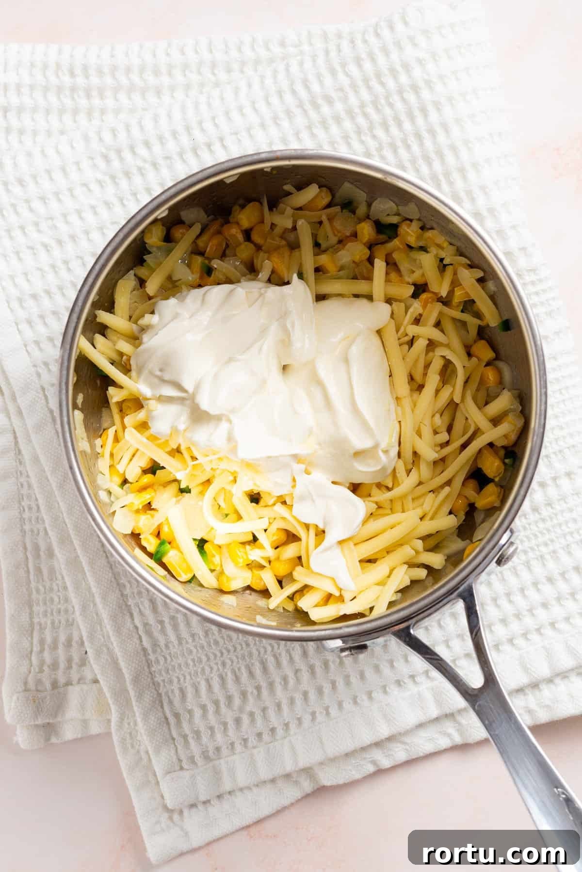 Spicy Jalapeño Corn Salad Bowl 6 An overhead image of cream cheese, sour cream, cheddar cheese added to the saucepan to melt.