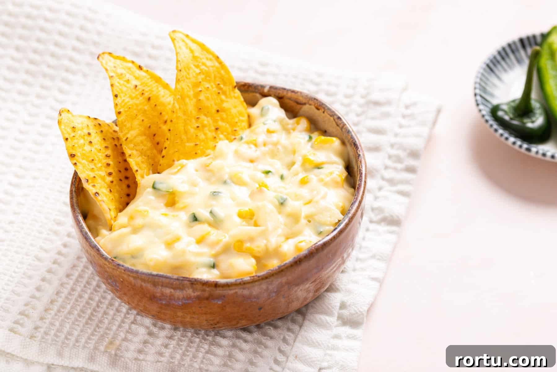 Spicy Jalapeño Corn Salad Bowl 9 An image of jalapeno corn in a wooden bowl with tortilla chips on the side.