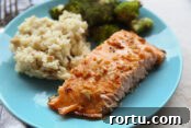 A blue plate with salmon, risotto, and broccoli. In the top left corner in the background is a fork head.