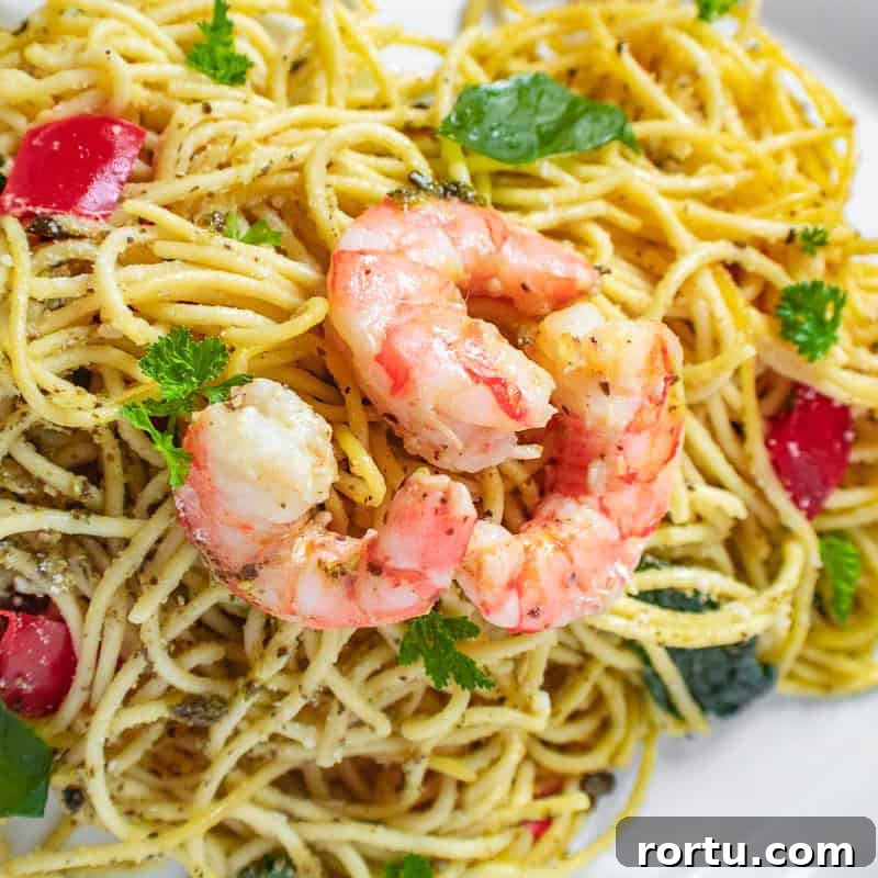Seasoned shrimp on pesto infused spaghetti.