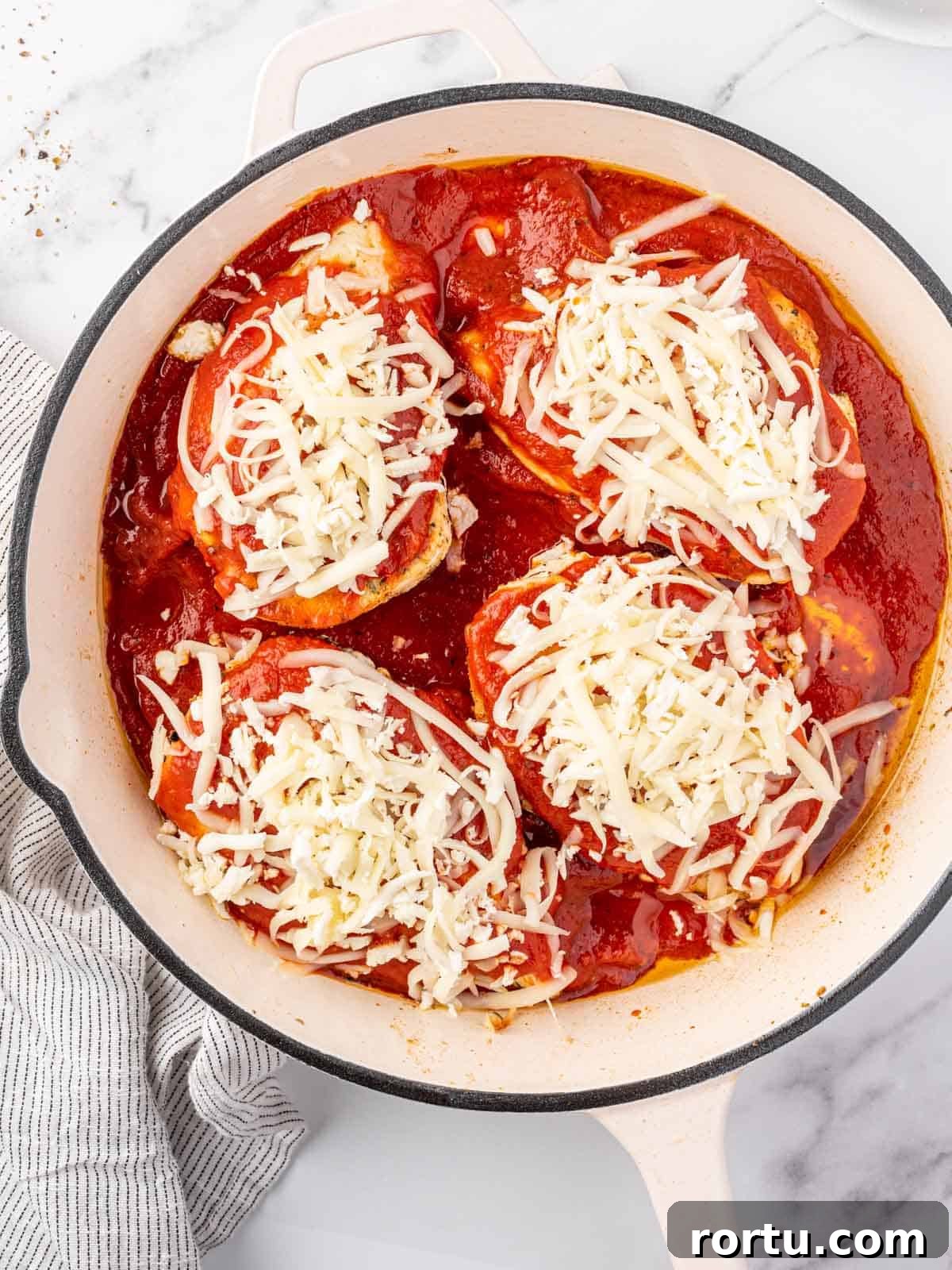 Chicken topped with sauce and cheese.