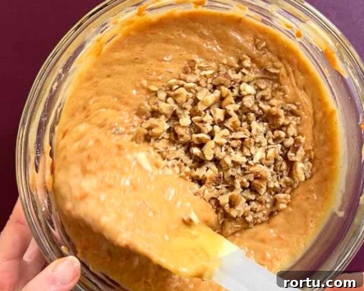 Ultimate Carrot Cake with Light Fluffy Cream Cheese Frosting 12 fold walnuts into carrot cake batter