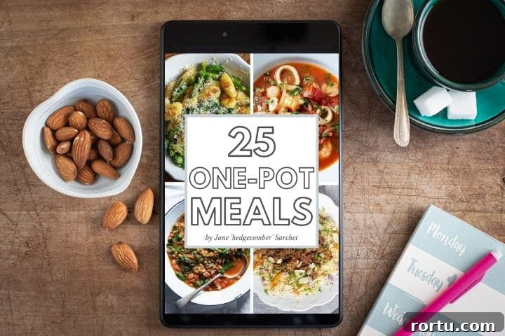 wooden surface with small bowl of almonds, green cup and saucer of black coffee, meal planning notebooks and ipad with one pot meals ebook open
