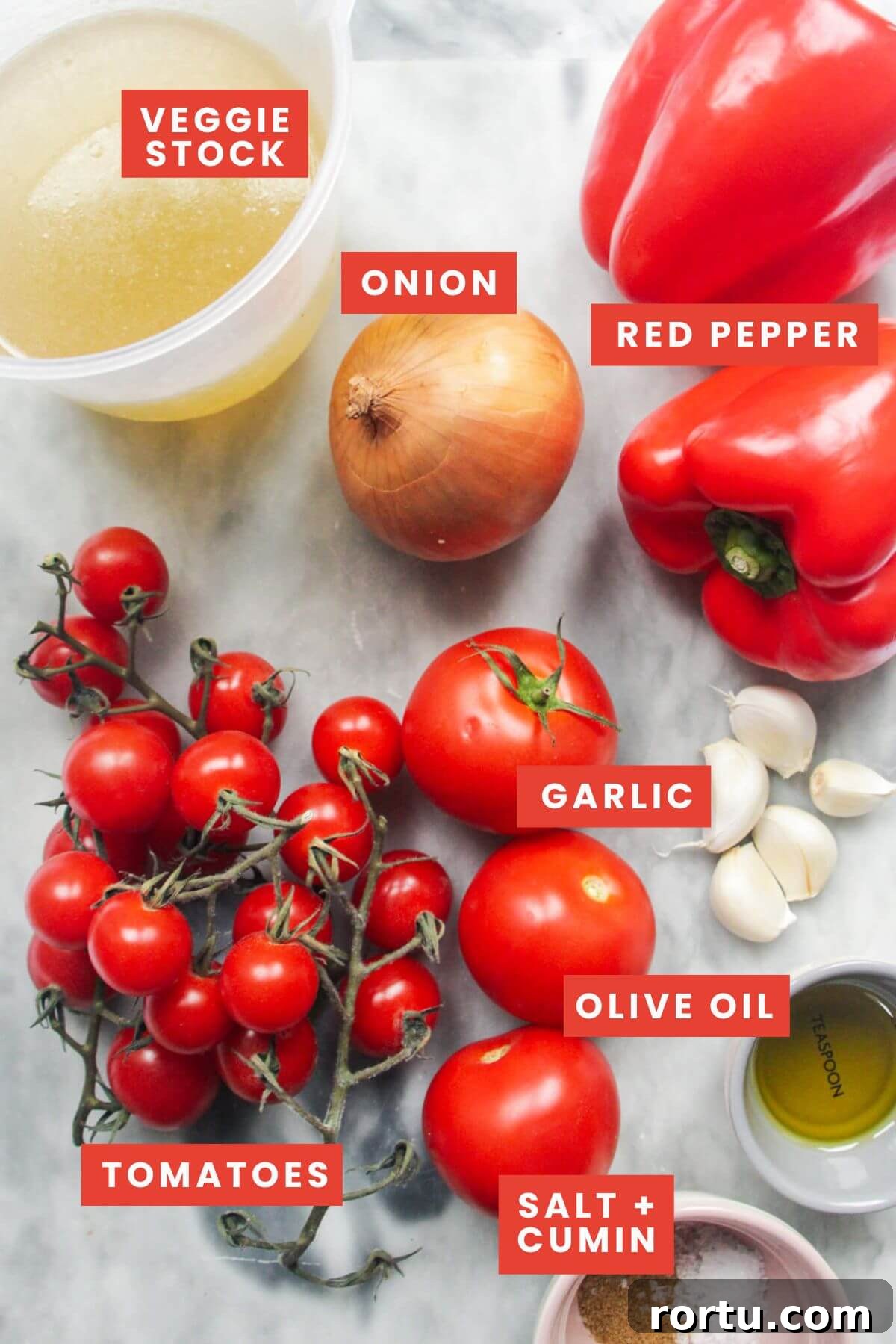 Ingredients for roasted tomato and red pepper soup laid out on a marble background.
