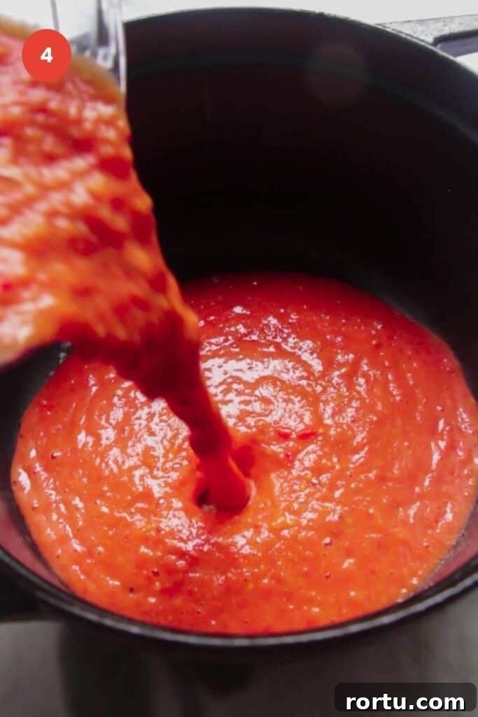 Tomato soup being poured into a large pot.