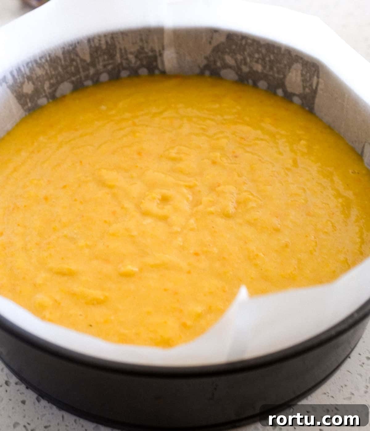Flourless orange cake batter sits in a baking tin, ready to be baked