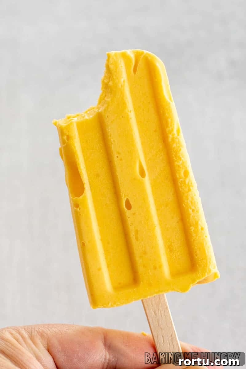 hand holding up mango popsicle