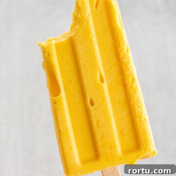 hand holding up mango popsicle