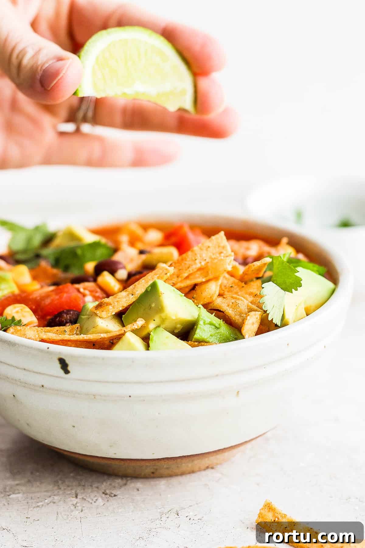 Chicken Tortilla Soup Recipe with Crock Pot and Instant Pot Options 9 A lime wedge being squeezed over a bowl of chicken tortilla soup.