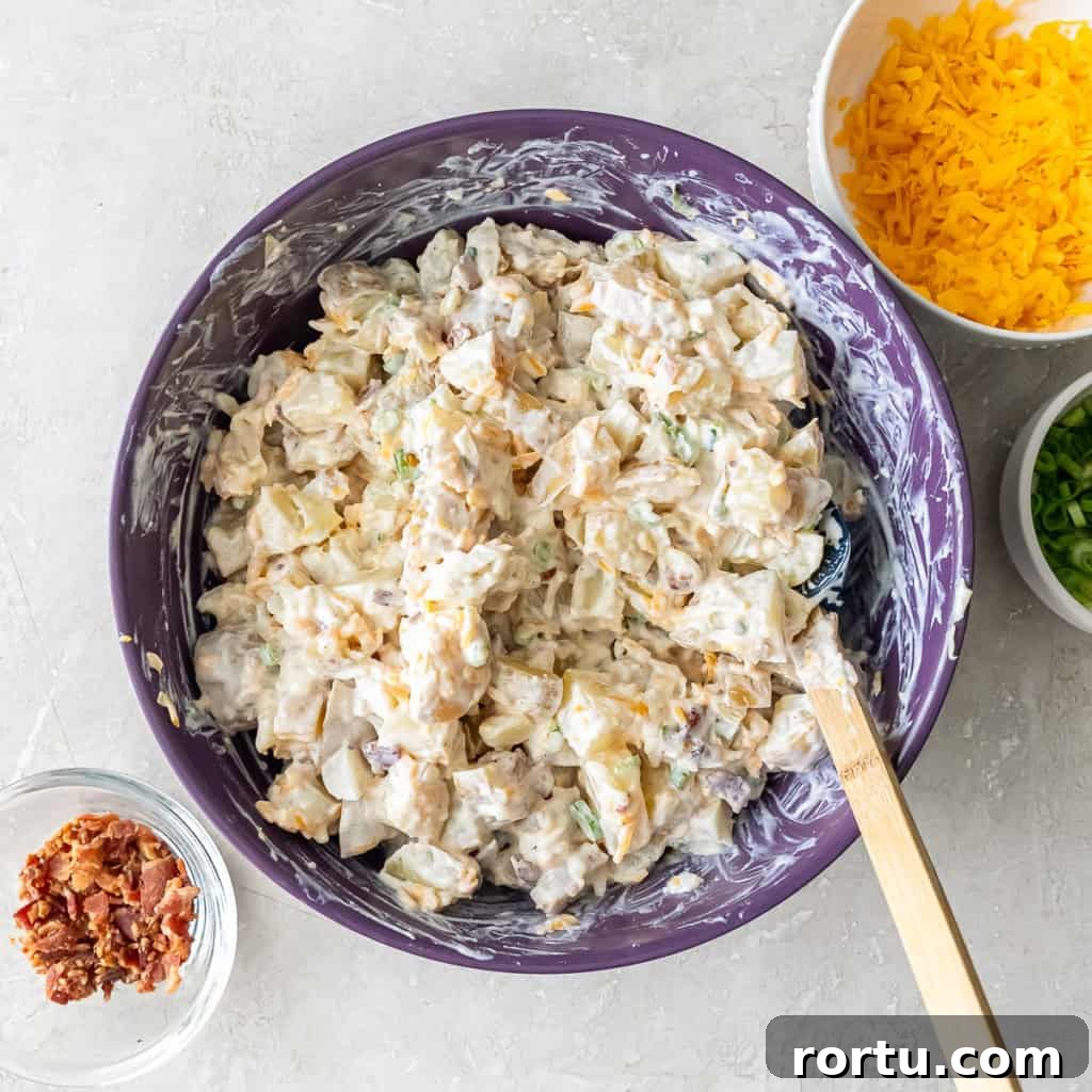Potato mixture combined with sour cream, cheese, green onions, and bacon in a purple mixing bowl.