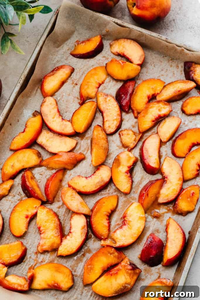 A sheet pan lined with parchment paper, with the cinnamon sugar tossed peach slices.