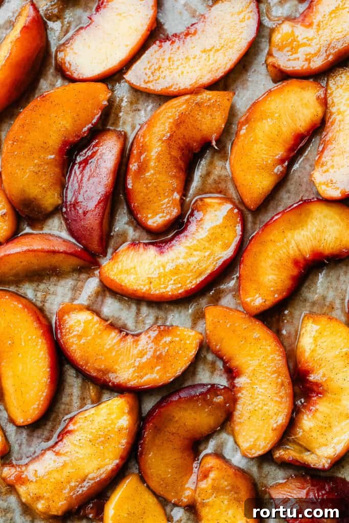 Juicy roasted peaches on a sheet pan.
