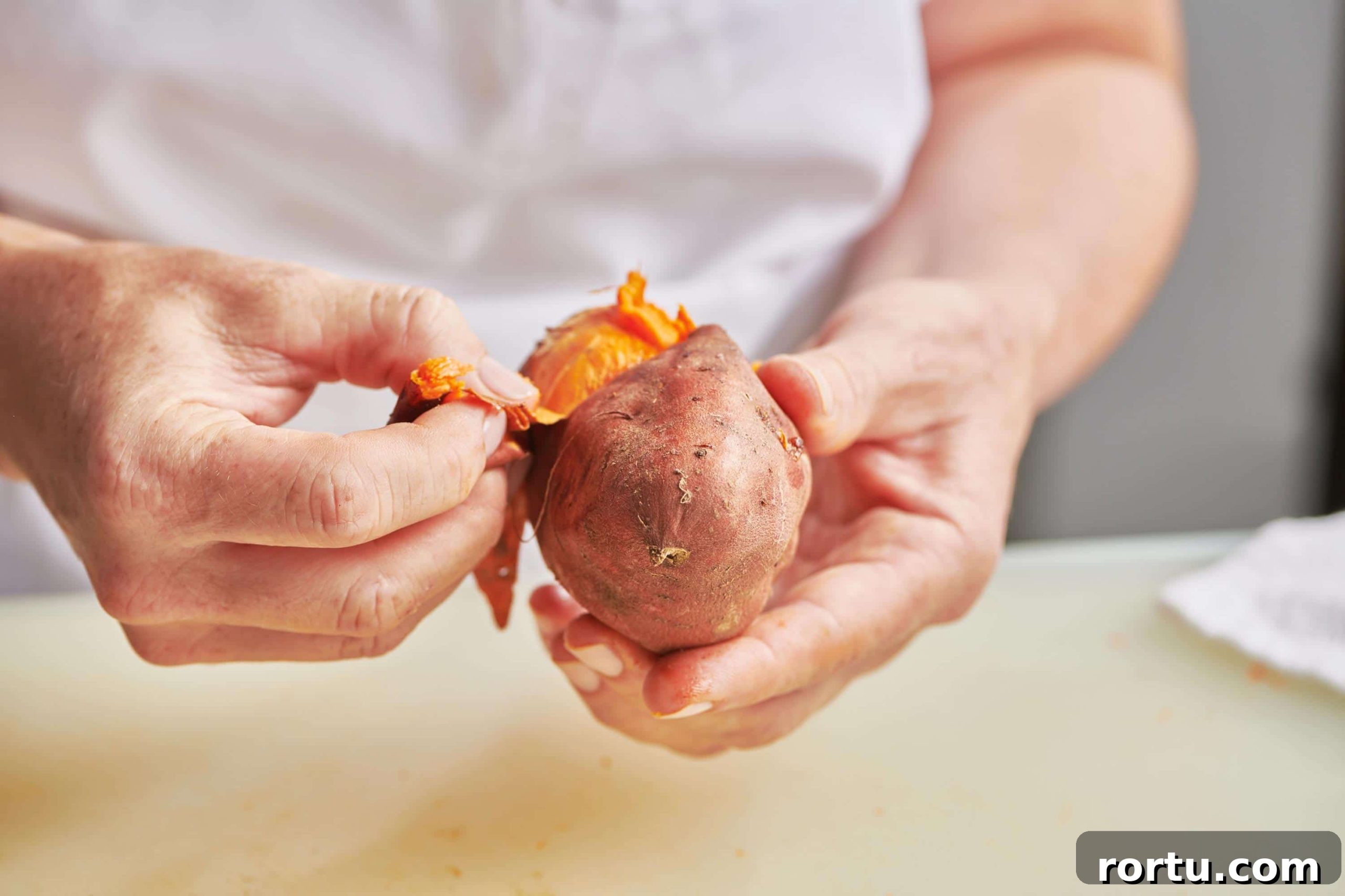 Woman peeling baked sweet potato.
