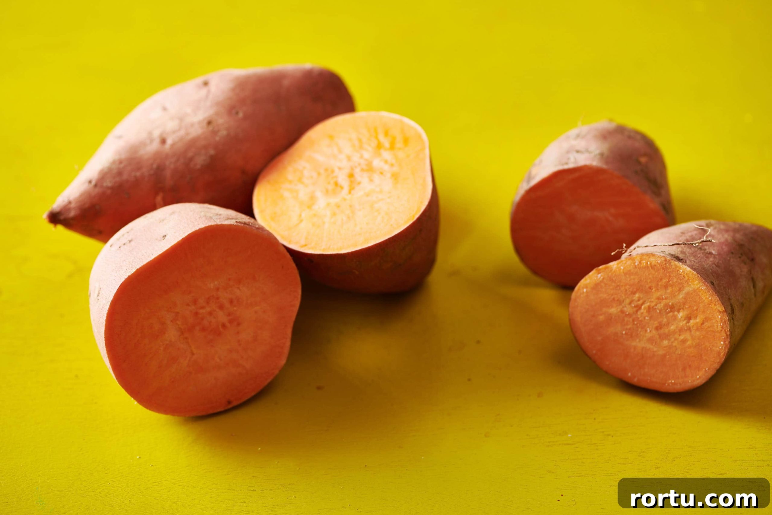 Several halved sweet potatoes on a chartreuse table.