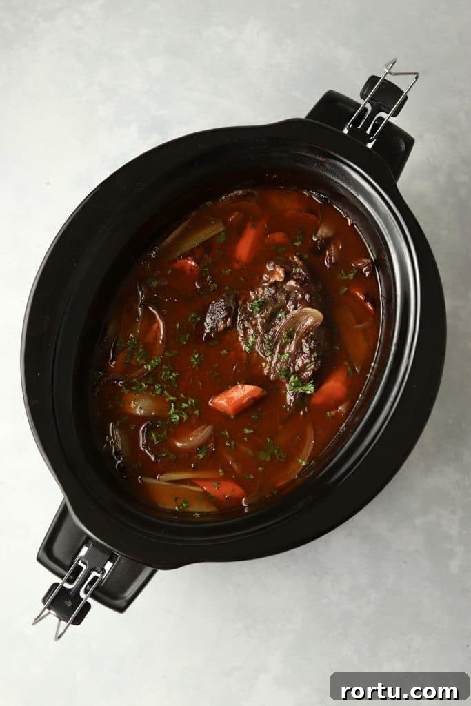 cooked pot roast with veggies and gravy in crockpot