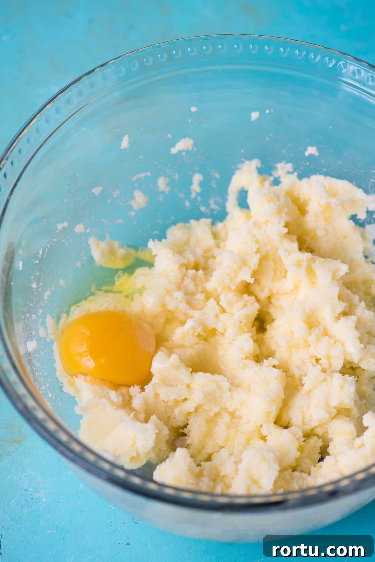 cookie dough with egg in a glass bowl on blue background