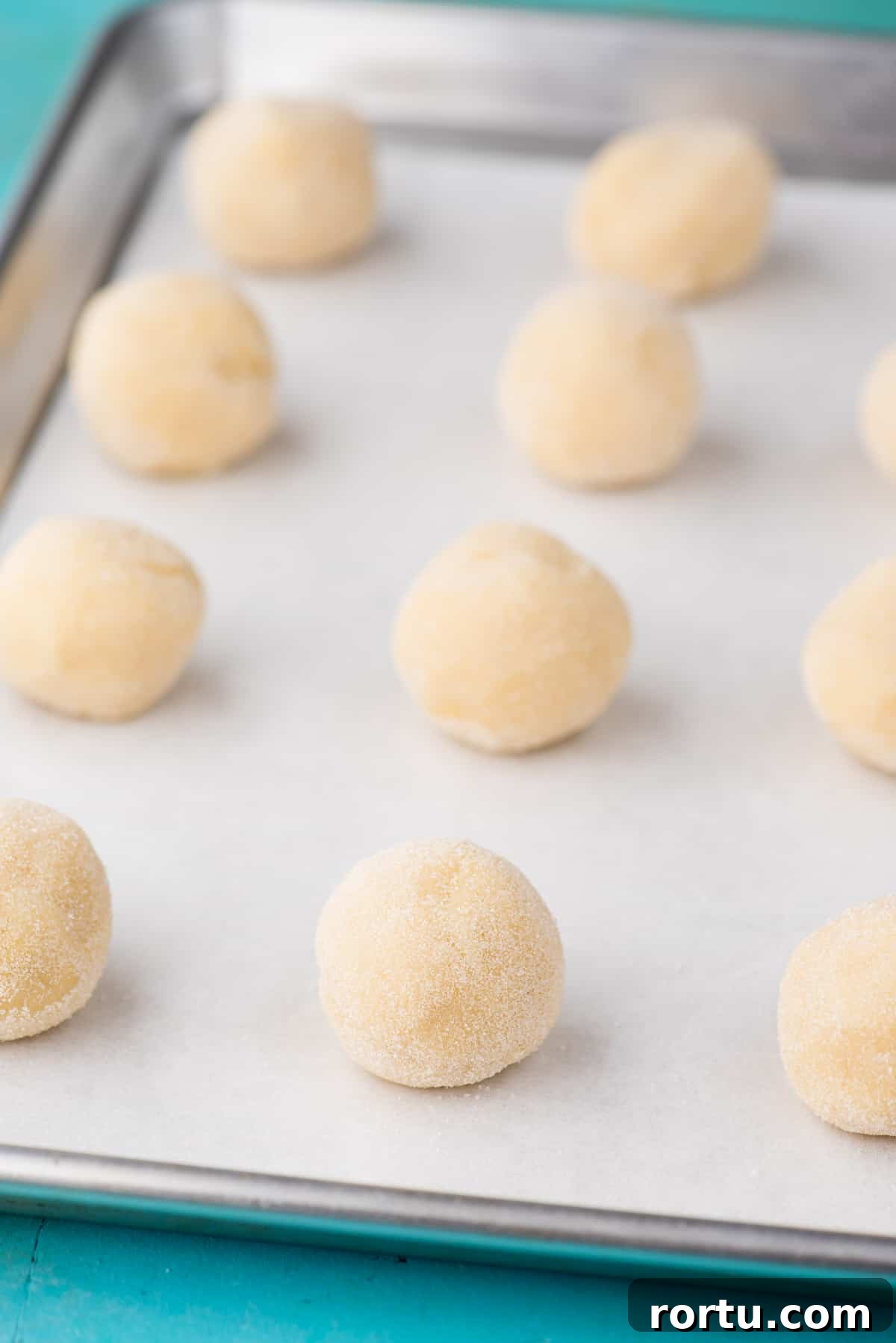 lemon cookie dough balls on baking sheet with parchment paper
