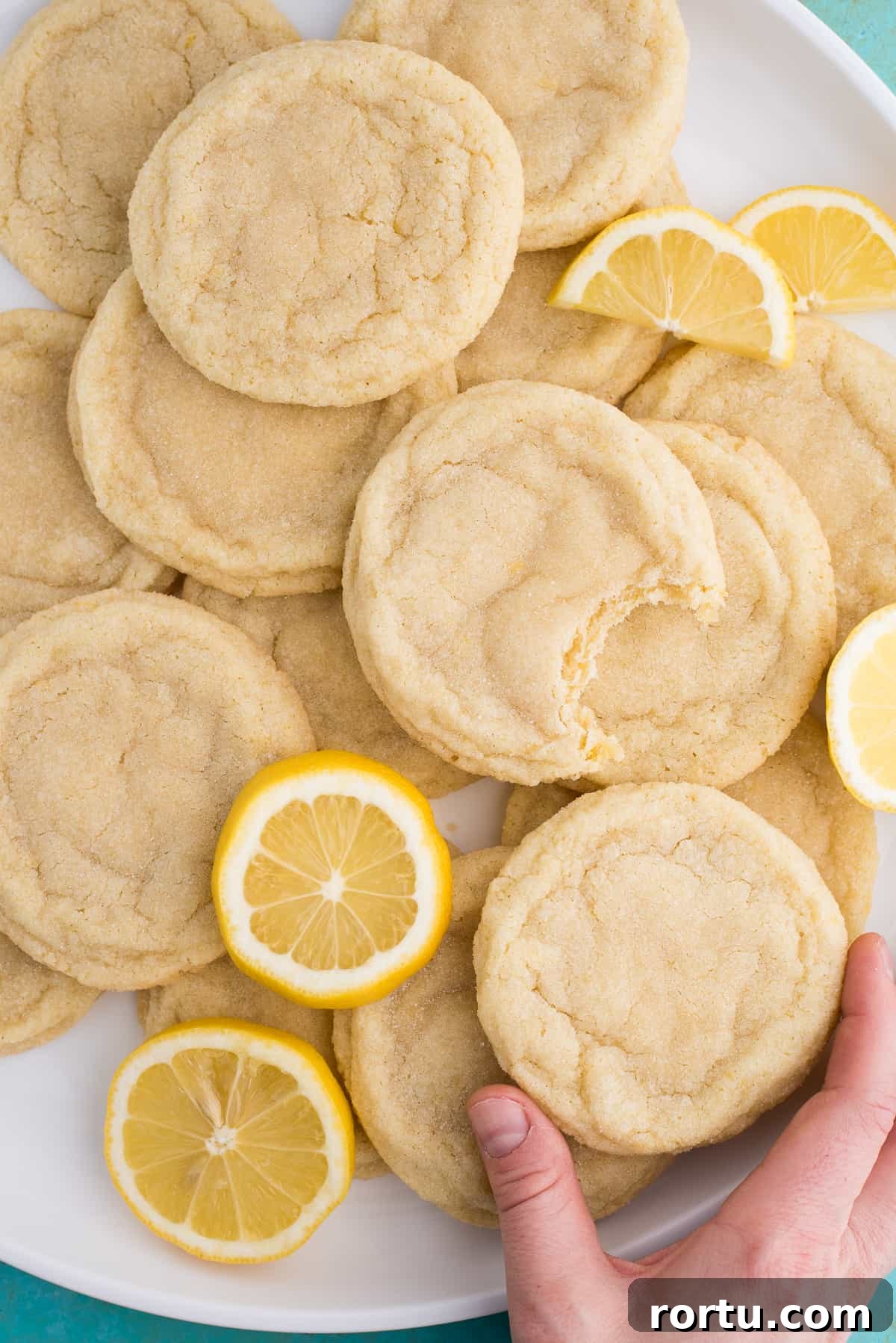lemon sugar cookies with lemon slices on white plate on blue background