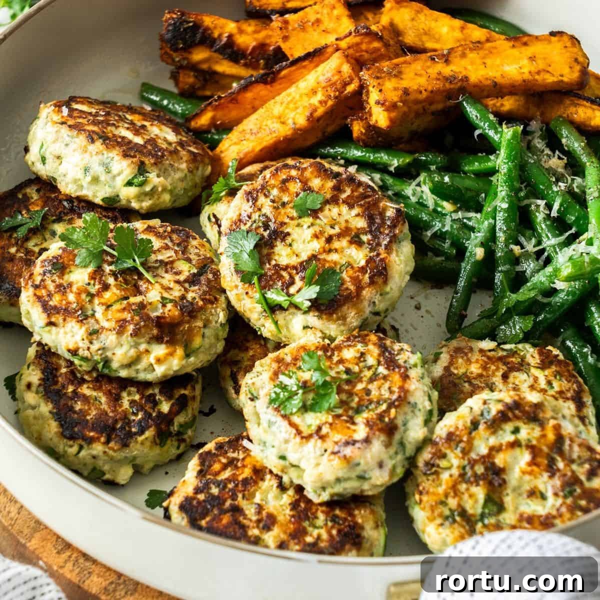 Round dish of Chicken Rissoles, with some green beans and sweet potato wedges on the side.