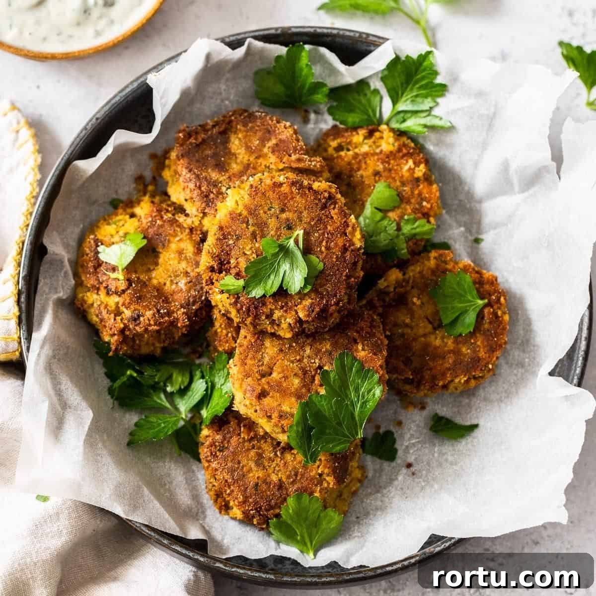 Round dish of cooked patties sitting on some baking paper, garnished with parsley.