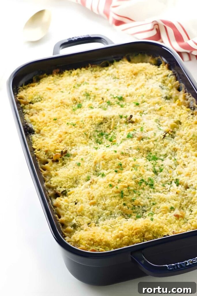Creamy Turkey Tetrazzini Recipe for Leftovers and Holiday Meals 2 Baked tetrazzini casserole with melted cheese and parsley in a dark rectangular dish.