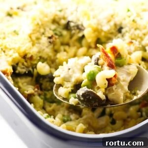 Creamy Turkey Tetrazzini Recipe for Leftovers and Holiday Meals 5 Creamy tetrazzini in casserole, spoon lifting a serving.