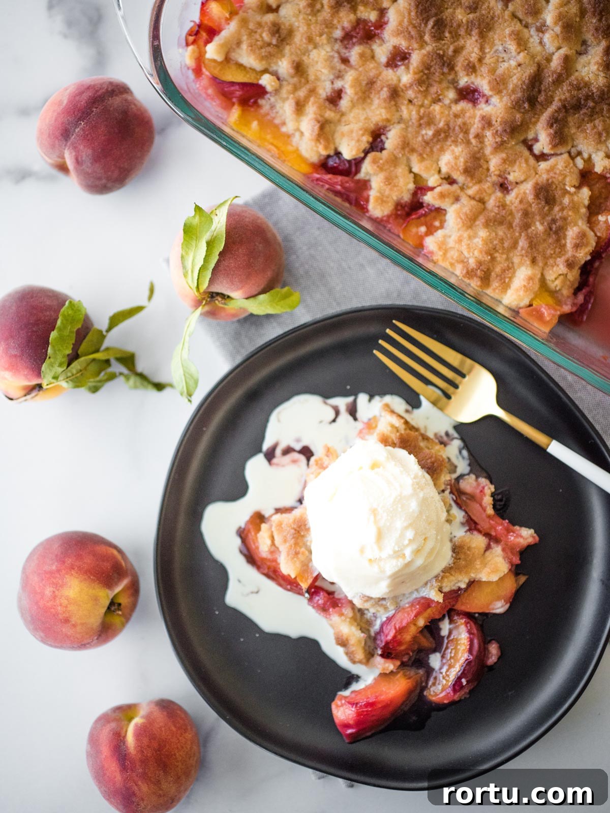peach cobbler topped with ice cream on a black plate