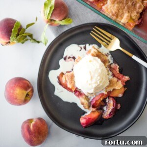 peach cobbler on a black plate topped with ice cream